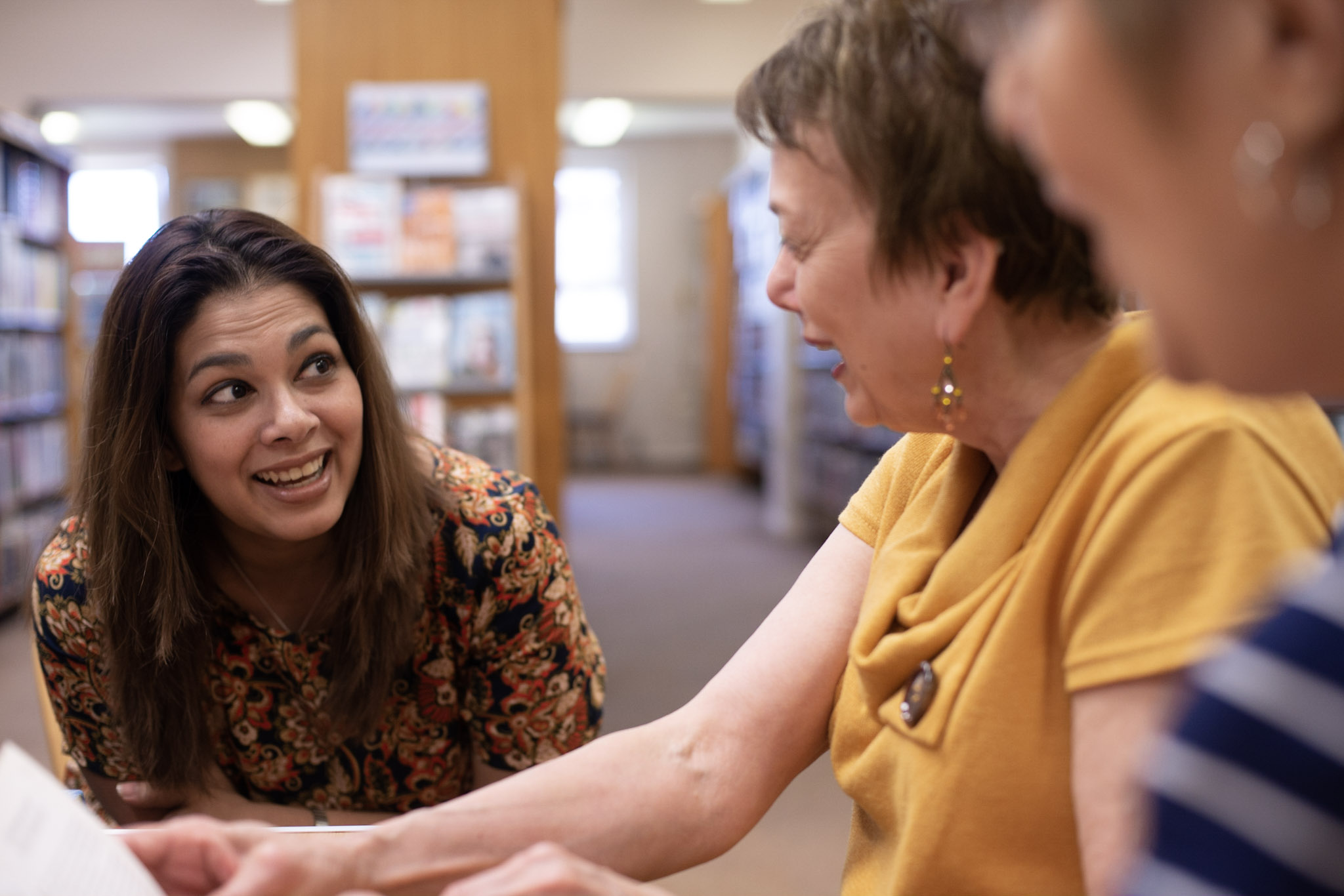 Two women are laughing in a library.