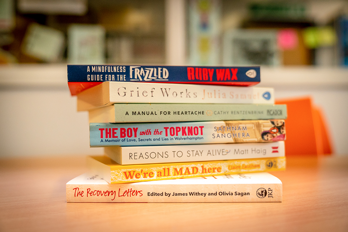 Photo of a stack of some Reading Well books on a table. 